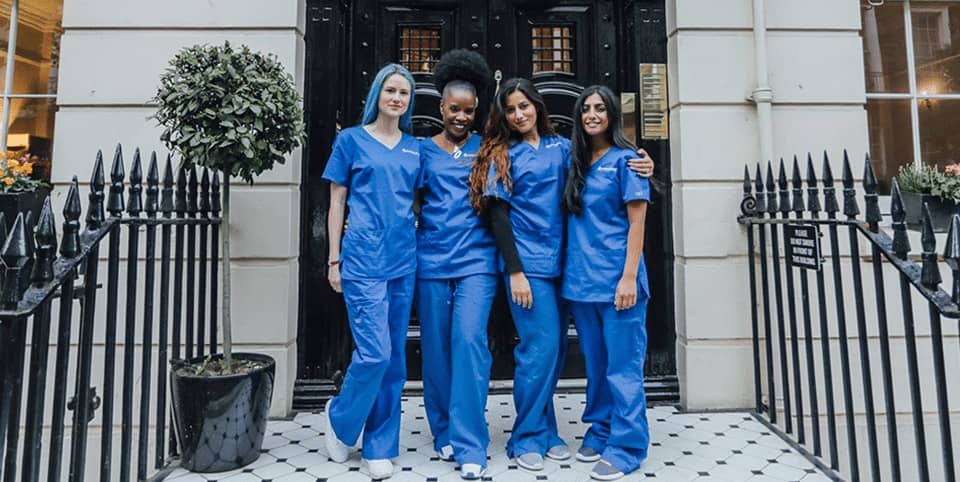 Four nurses in blue scrubs outside a Georgian clinic entrance at our Harley Street clinic, EMsculpt NEO body sculpting London